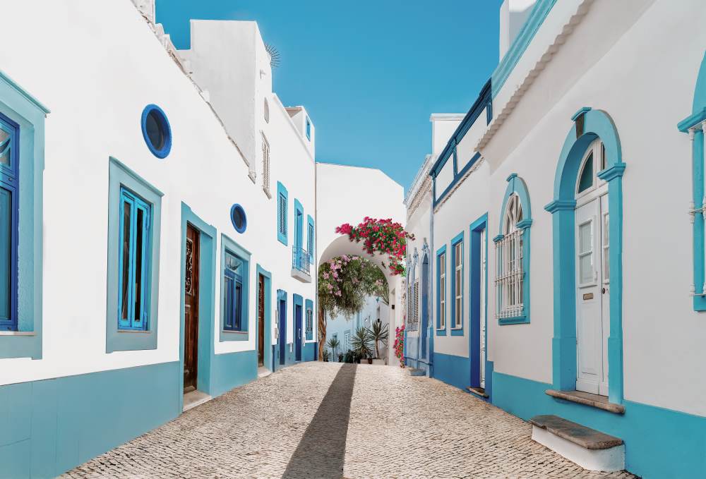 QStreet in fishermen village with white and blue houses and typical Portuguese pavement in Olhao, Algarve region portugal